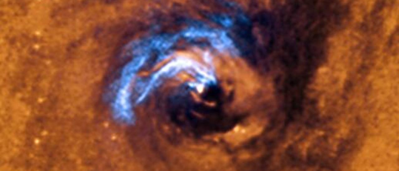 The  image shows the process of nuclear feeding of a black hole in the galaxy NGC 1566, and how the dust filaments - seen in white-blue colors- are trapped and rotating  in a spiral around the black hole  until the black hole  swallows them. Credit: ESO.