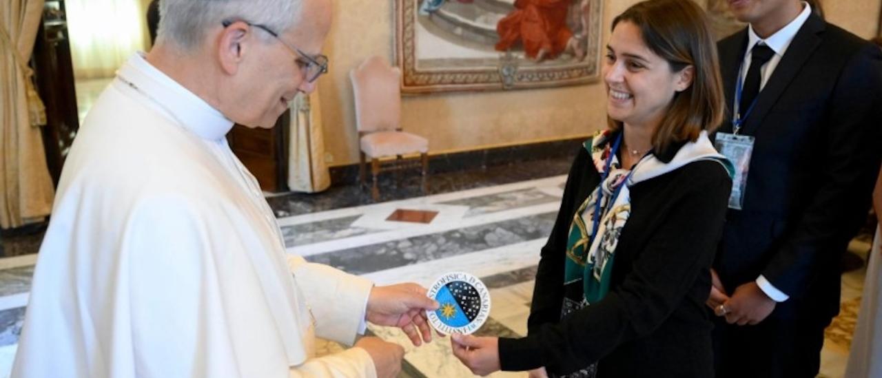 Image of the moment when doctoral students Stella Tsilia and Jun-Yan Zhang (Jerry) present Pope Leo XIV with the sticker bearing the IAC logo.