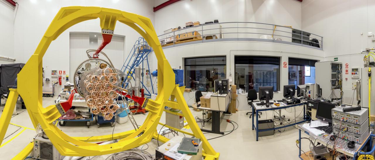 Panoramic view of one the areas of the Assembly, Integration and Verification room. Large laboratory with work benches and multiple electronic devices and computers, with a large mechanical structure in assembly phase