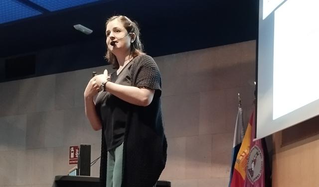 Una mujer habla sonriendo a un público que está fuera de la imagen