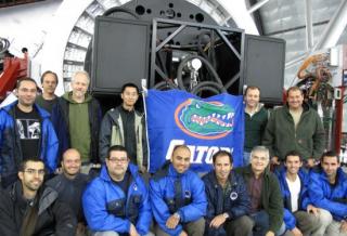 Some of the team responsible for the first installation and adjustment of CanariCam at the Gran Telescopio CANARIAS. The photograph shows the instrument installed at the Nasmyth focus, just above the "Gators" flag attached to the camera by University of F Some of the team responsible for the first installation and adjustment of CanariCam at the Gran Telescopio CANARIAS. The photograph shows the instrument installed at the Nasmyth focus, just above the "Gators" flag attached to the camera by University of F